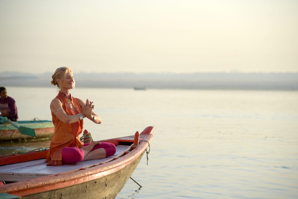 Tourist doing yoga in boat at Varanasi